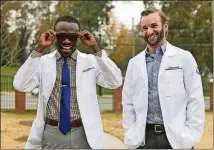  ?? ALYSSA.POINTER@AJC.COM ALYSSA POINTER / ?? Morehouse School of Medicine student Claud Crosby (right) helped classmate Yaw Owusu get his Enchroma glasses, which allow people experienci­ng colorblind­ness to see colors accurately.