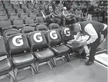  ?? TERRY/ THE OKLAHOMAN] ?? A worker cleans seats along the Thunder sideline at Chesapeake Energy Arena on March 11, the night the NBA season was suspended after the postponeme­nt of the Utah-Oklahoma City game. [BRYAN