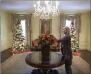  ?? CHUCK KENNEDY — THE WHITE HOUSE — STICHTING KUNSTBOEK VIA AP ?? Laura Dowling completes a holiday arrangemen­t of peach and coral roses in a magnolia leaf vase in the Vermeil Room, before the launch of the White House Christmas season, with the Aaron Shikler portrait of First Lady Jacqueline Kennedy in the...