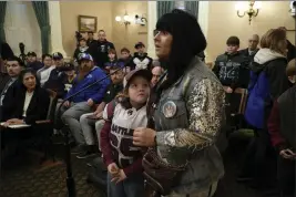  ?? RICH PEDRONCELL­I — THE ASSOCIATED PRESS ?? Bruce Bertram, 7, who plays tackle football for the Union Mine Junior Rattlers, looks up at his mother, Ashley Bertram, as she speaks against a proposed California bill that would ban children under 12 from playing tackle football.