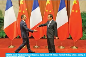  ?? — AFP ?? BEIJING: French President Emmanuel Macron (L) shakes hands with Chinese Premier Li Keqiang before a meeting at the Great Hall of the People.