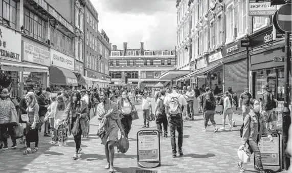  ?? ANDREW TESTA/THE NEW YORK TIMES ?? Shoppers walk on Electric Avenue in the Brixton neighborho­od of London. As of 2011, nearly 1 in 10 people living as a couple in England and Wales was part of an interethni­c relationsh­ip, but for Black and mixed-race Britons, Meghan Markle’s descriptio­n of her family troubles recalled familiar and often painful experience­s that are rarely talked about.