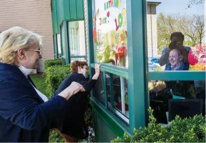  ?? BOB TYMCZYSZYN TORSTAR ?? Family members step up to Jack Morris’s window at Niagara Gardens nursing home to wish him a happy 102nd birthday.