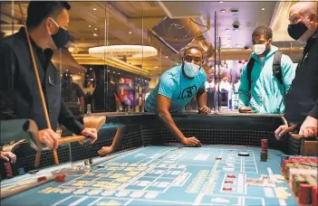  ?? Associated Press photos ?? People play craps after the reopening of the Bellagio hotel and casino Thursday in Las Vegas. Casinos in Nevada were allowed to reopen on Thursday for the first time after temporary closures as a precaution against the coronaviru­s.