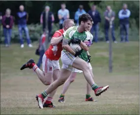  ??  ?? Kilmac’s Michael Masterson drives through as Tinahely’s Tony Darcy tries to put a stop to his gallop during the IFC clash in Ashford. Photo: Barbara Flynn