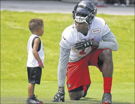  ?? CURTIS COMPTON / CCOMPTON@AJC.COM ?? Receiver Julio Jones pauses to talk with a young fan as he leaves the field at the end of the first day of the Falcons’ training camp at Flowery Branch. The Falcons had their first drills under new coach Dan Quinn, former Seattle defensive coordinato­r.