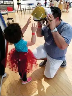  ??  ?? FATHER AND DAUGHTER DON A SPACE HELMET so they can travel in the space capsule at the Children’s Museum of Yuma County.