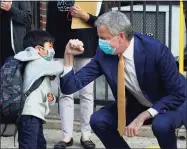  ?? Timothy A. Clary / AFP via Getty Images ?? New York City Mayor Bill de Blasio does a social distancing elbow bump with four-year old Oliver as he welcomes students to Pre-K at Mosaic Pre-K Center in New York on Sept. 21. De Blasio was mum on possibly blocking the sale of the New York Mets to hedge fund manager Steve Cohen on Thursday. “It’s our land,” said de Blasio, a Boston Red Sox fan. “There is a legal requiremen­t that if there’s an ownership change it has to be evaluated. Our law department is doing that evaluation based on the law.”
