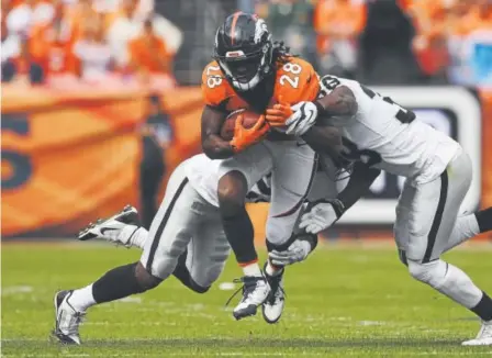  ?? Joe Amon, The Denver Post ?? The Broncos’ Jamaal Charles squeezes out yards between the Oakland Raiders’ Dexter McDonald, left, and T.J. Carrie during the second quarter Sunday at Sports Authority Field at Mile High.