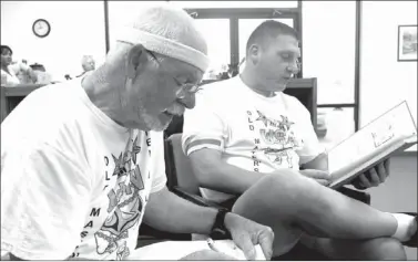  ?? LYNN KUTTER ENTERPRISE-LEADER ?? Ed Marshall, left, and Travis Biswell ran 10 miles together as comrades who have both achieved the rank of U.S. Navy Master Chief Petty Officer. As part of the induction, Master Chief selectees have others sign a special book. Marshall is signing...