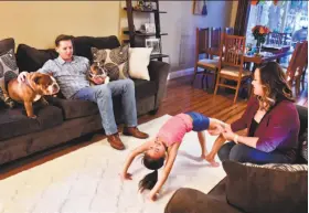  ?? Stuart Palley / Special to The Chronicle ?? Lola Bodenhamer, 9, works on a gymnastics move while her father and mother, Mark Bodenhamer and Tallia Hart, watch in their Orange County home.