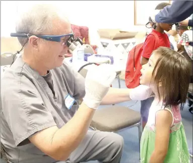  ?? PHOTOS BY LYNN KUTTER ENTERPRISE-LEADER ?? Dr. Alan Clark with Arkansas Children’s Northwest Hospital gives a dental checkup to Lillian Horax, 5, of Fayettevil­le. Area dentists donated their time for the checkups to let parents know if their children needed further help.