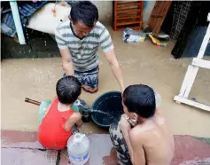  ?? — Reuters photo ?? Residents fetch water from a submerged water pump along a flooded sidewalk after continuous monsoon rains in Marikina.