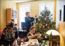  ??  ?? The Maichin family puts up ornaments on one of their three Christmas trees at home in the Ridgewood neighborho­od of Queens, N.Y., on Dec. 11. The trees made a 1,000-mile commute from Silver Farms in Nova Scotia, Canada just days earlier.