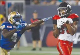  ?? The Canadian Press ?? Winnipeg Blue Bombers defensive back Roc Carmichael, left, can’t stop Calgary Stampeders receiver Kamar Jorden from hauling in a touchdown pass during the second half of Friday’s game in Winnipeg.