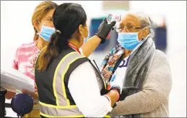  ?? A PASSENGER Al Seib Los Angeles Times ?? service representa­tive for Avianca Airlines takes the temperatur­e of Eva Zapata at LAX before her f light to El Salvador in November.