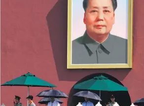  ??  ?? Uniformed and plaincloth­es security personnel with umbrellas on duty near a portrait of late Chinese leader Mao Zedong in Beijing yesterday.