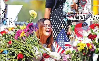  ??  ?? Marjory Stoneman Douglas High School former student Ariana Gonzalez weeps Friday at a cross of slain Marjory Stoneman Douglas coach Aaron Feis, on a hill honoring those killed in Parkland, Fla.