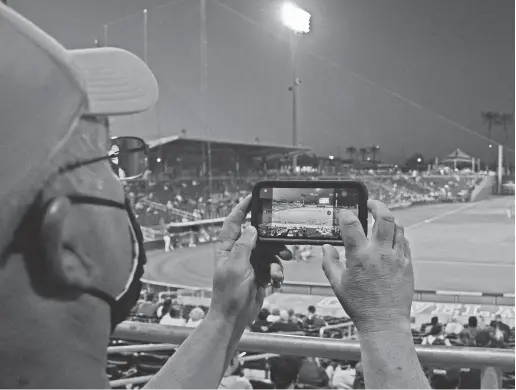  ?? JOE CAMPOREALE/USA TODAY SPORTS ?? A fan takes a photo on their phone of a general view of game action between the Cincinnati Reds and the Los Angeles Angels during the second inning of a spring training game at Goodyear Ballpark.