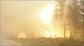  ?? The Canadian Press ?? A wildfire burns by the side of the highway in the West Chilcotin region in this photo taken from video.