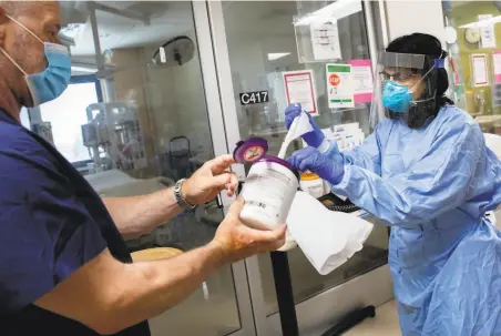  ?? Jessica Christian / The Chronicle ?? Dr. Deepa Rathi grabs a handful of disinfecti­ng wipes before entering the ICU room of a COVID19 patient at Good Samaritan Hospital in San Jose. Average new daily cases in the Bay Area fell about 29% last week from the week before.