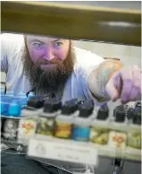  ??  ?? Grand Vape Co. owner/operator Rob Graveur restocks vape juices.