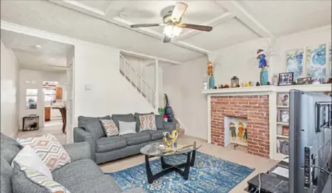  ??  ?? The living room has a brick fireplace, a built-in bookcase and a coffered ceiling.