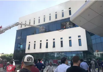  ?? — AFP photo ?? Firefighte­rs and onlookers gather in front of the headquarte­rs of Libya’s National Oil Company in Tripoli.