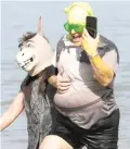  ?? ?? Jose Herrera (right), who dressed as Shrek, holds his phone up as he wades through the chilly water.