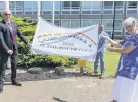  ?? Paul Smith Associates ?? Christine Lincoln with the memorial flag being held by John Lewis, right, and Simon Lewis who created the HeathLive community website at Heath Business and Technical Park in Runcorn.