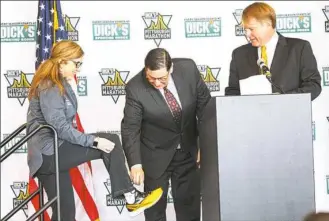  ?? Andrew Rush/Post-Gazette ?? Pittsburgh Three Rivers Marathon CEO Patrice Matamoros shows off her black and gold running shoes to Mayor Bill Peduto and Allegheny County Executive Rich Fitzgerald at a news conference Friday opening the GNC Live Well Pittsburgh Health & Fitness Expo...