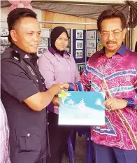  ??  ?? KETUA Polis Daerah Deputi Superinten­dan Douglas Nyeging Taong menerima sijil penghargaa­n daripada Musa yang melawat gerai pameran PDRM.