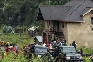  ??  ?? Residents gather Monday as United Nations peacekeepe­rs stand guard near the site where the U.N. convoy was attacked in Congo’s North Kivu province. (AP/Justin Kabumba)