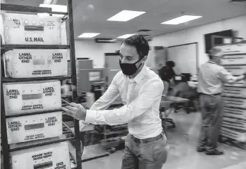  ?? CHANDAN KHANNA AFP/Getty Images/TNS, file ?? Electoral workers help with the vote-by-mail ballot scanning at the Miami-Dade County Election Department in Florida on Nov. 3, 2020. By the time the 2020 election ended, 73 million Americans had voted with a mailed-out ballot.