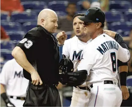  ?? WILFREDO LEE/AP ?? Miami Marlins manager Don Mattingly, right, holds back Miguel Rojas as Rojas argues with home-plate umpire Mike Estabrook during a game against the Nationals. Mattingly believes the Marlins have recently been victimized by a few incorrect strike calls.