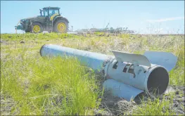  ?? Andrii Marienko The Associated Press ?? A fragment of a Russian missile is seen in the foreground as a farmer works on his field on Saturday in Izium, Kharkiv region, Ukraine.