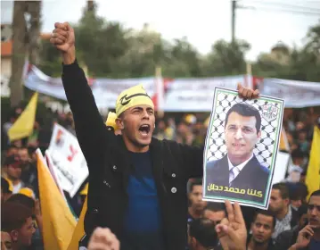  ?? (Reuters) ?? A MAN holds a poster of former Gaza Fatah leader Mohammed Dahlan during a protest against PA President Mahmoud Abbas in Gaza City in 2014.