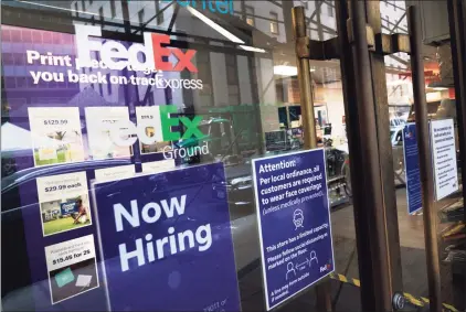  ?? Associated Press ?? A “Now Hiring” sign in the window of a FedEx office on Oct. 26 in New York. Carriers like FedEx and UPS are ramping up their holiday hiring while asking store clients to move their shipping volume on lighter days in their network.