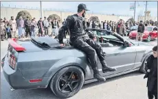  ?? ?? Hashmatull­ah Rahbar, chief at National Sports Car Racing Federation of Afghanista­n riding on the back of a modified car competing in a drag race during a car racing event in Kabul.