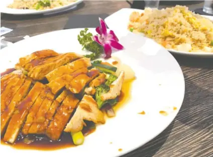  ?? PHOTO BY SUSAN PIERCE ?? Teriyaki Chicken at Fulin’s Asian Cuisine is plated with an orchid garnish. Fried rice with shrimp, back right, incorporat­es about a dozen shrimp.