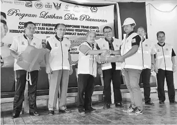  ??  ?? Paulus (third left) flanked by Mohd Firdaus on his right and Hasbi, hands over a safety jacket to a CERT Batu Danau member during the ceremony.
