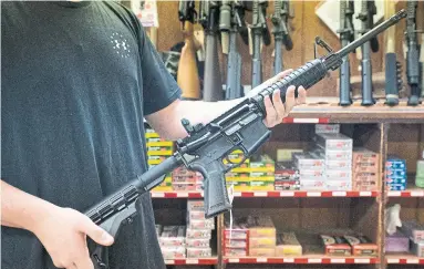 ?? ERIN SCHAFF THE NEW YORK TIMES FILE PHOTO ?? A gun shop employee displays an AR-15. “Assault weapons stand for the abhorrent ability to annihilate as many people as possible in a most violent way. Why would anyone have the desire to own such a weapon?” Julia Bowkun wonders.