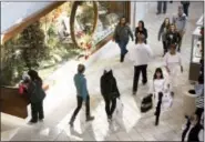  ?? HEATHER ROUSSEAU/THE ROANOKE TIMES VIA AP ?? Shoppers pass holiday decorated store front displays during Black Friday at Valley View Mall in Roanoke, Va.