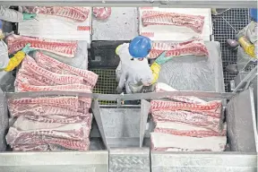  ??  ?? Butchers place pork ribs on a conveyor belt at a Smithfield Foods processing plant in Milan, Missouri. Smithfield, the world’s biggest pork producer, was acquired in 2013 by WH Group Ltd of China. Chinese firms have spent almost $52 billion on overseas...