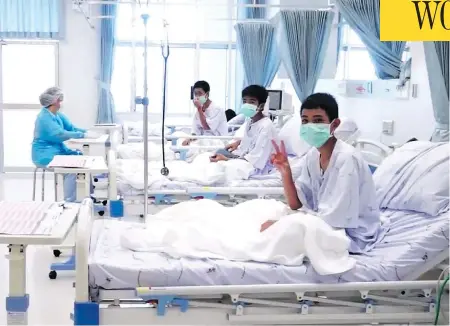  ?? THAI GOVERNMENT PUBLIC RELATIONS DEPARTMENT AND GOVERNMENT SPOKESMAN BUREAU / AFP / GETTY IMAGES ?? Members of the Wild Boars football team wave to the cameras in their hospital room in Chiang Rai, Thailand. The 12 boys rescued from a Thai cave were passed “sleeping” on stretchers through the passageway­s, a former Thai Navy SEAL said Wednesday, as details of the rescue mission emerged.