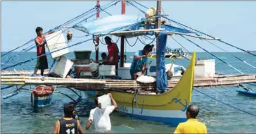  ?? TED ALJIBE/AFP ?? Crew members load supplies onto a fishing vessel anchored at the mouth of the South China Sea in Pangasina, the Philippine­s, as they prepare for a fishing expedition to Scarboroug­h Shoal in June.