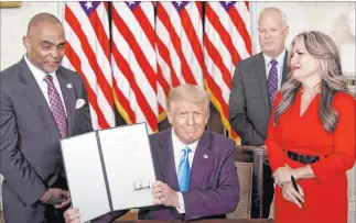  ?? White House ?? President Donald Trump holds up the pardon he gave Tuesday to Jon D. Ponder, left, founder of Las Vegas-based Hope for Prisoners, as Richard Beasley and Ponder’s wife, Jamie, look on.