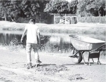  ?? JORGE COTA ?? >Un menor desparrama con sus pies la tierra conque tapa los baches.