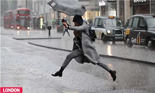  ??  ?? LONDON Water jump: Umbrella raised, a shopper takes a long leap over the torrent running down Oxford Street yesterday