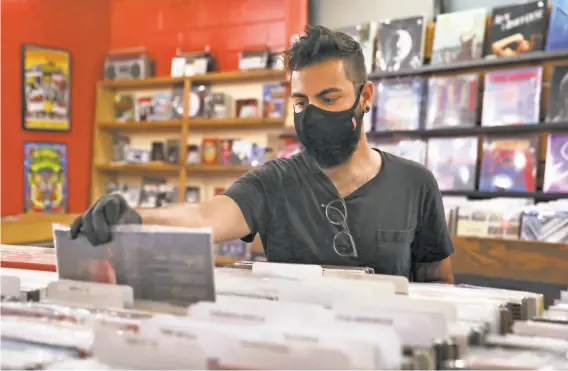  ?? Liz Hafalia / The Chronicle ?? Clinton Johnson of Oakland browses through albums this month at 1234 Go, wearing a mask and gloves that were given to him as he entered the store.